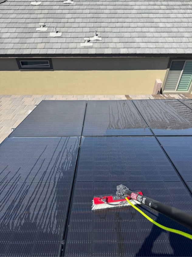 Close-up of water and soft brush cleaning solar panel surface on a Las Vegas residential rooftop